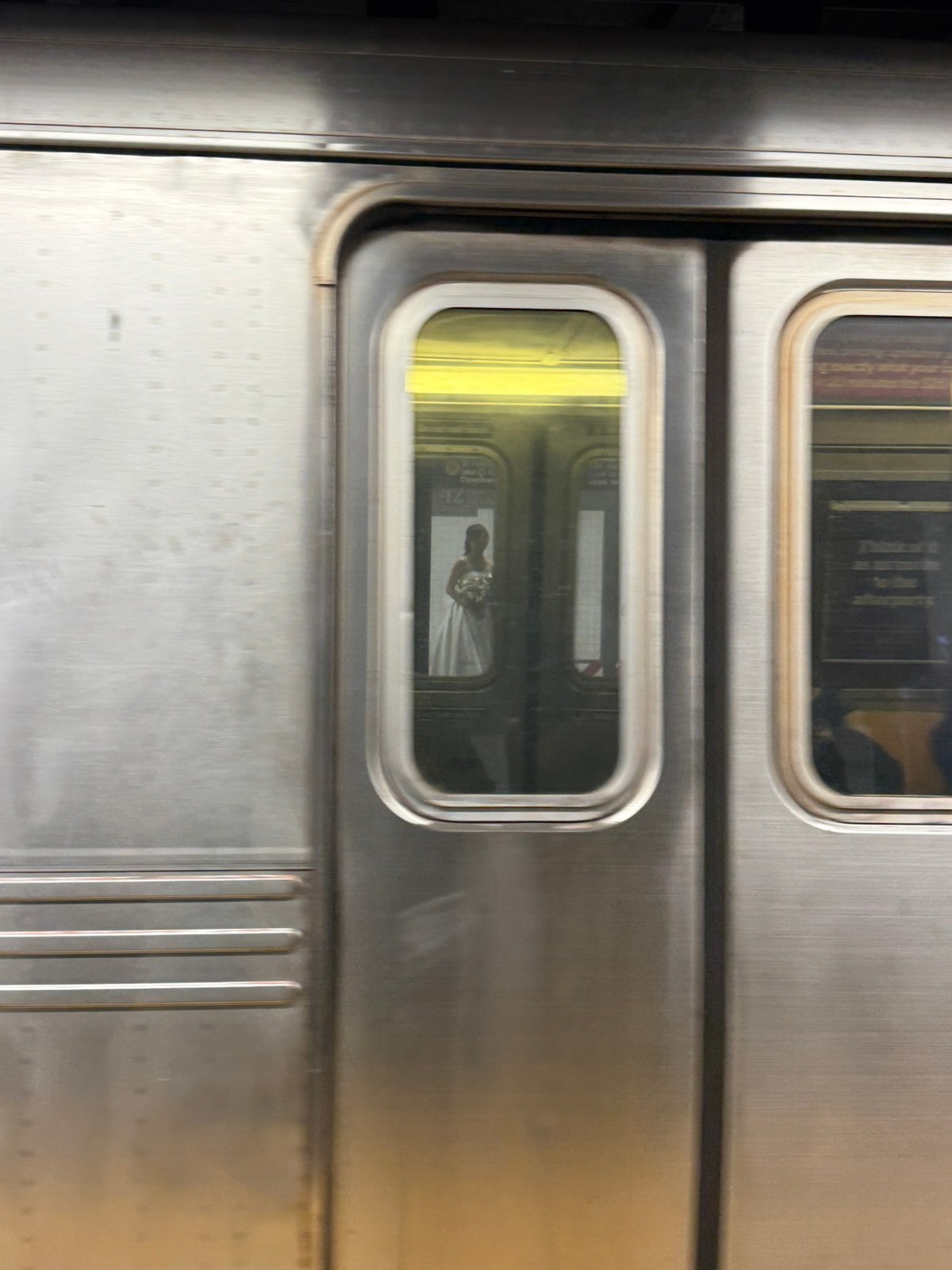 A bride seen through a subway car window